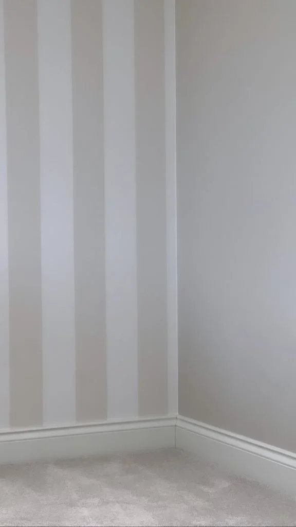white room with white striped wallpaper 