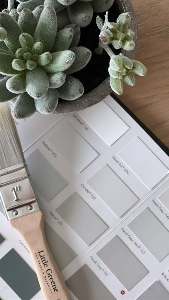 little greene paint card with a paintbrush on a wooden table with a green flower  