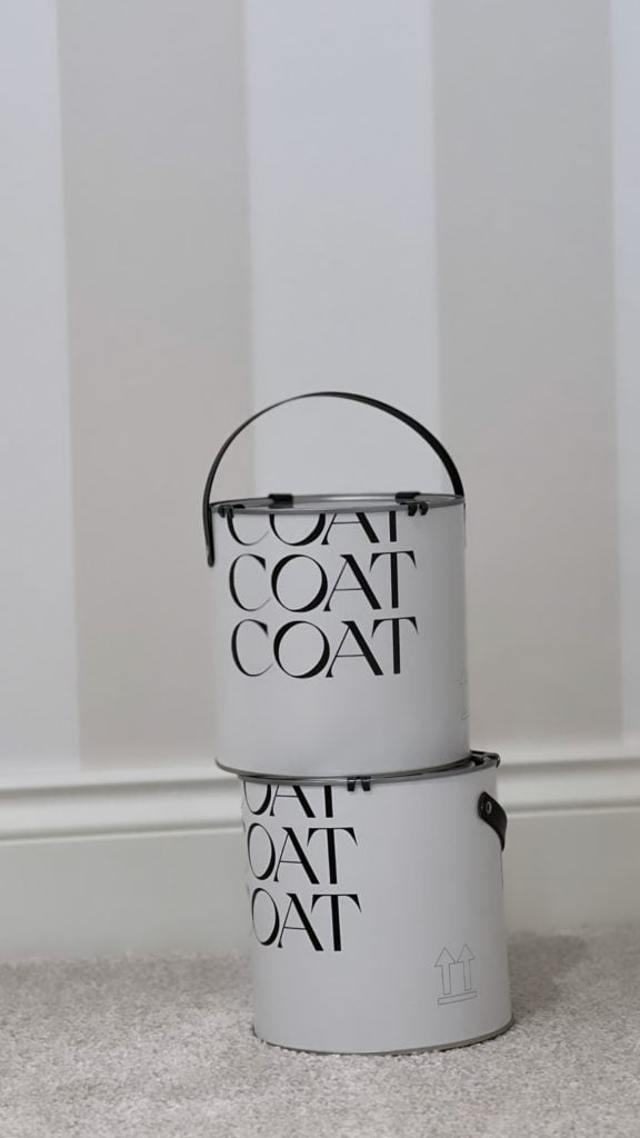 coat paints and paint tins against a wallpapered wall