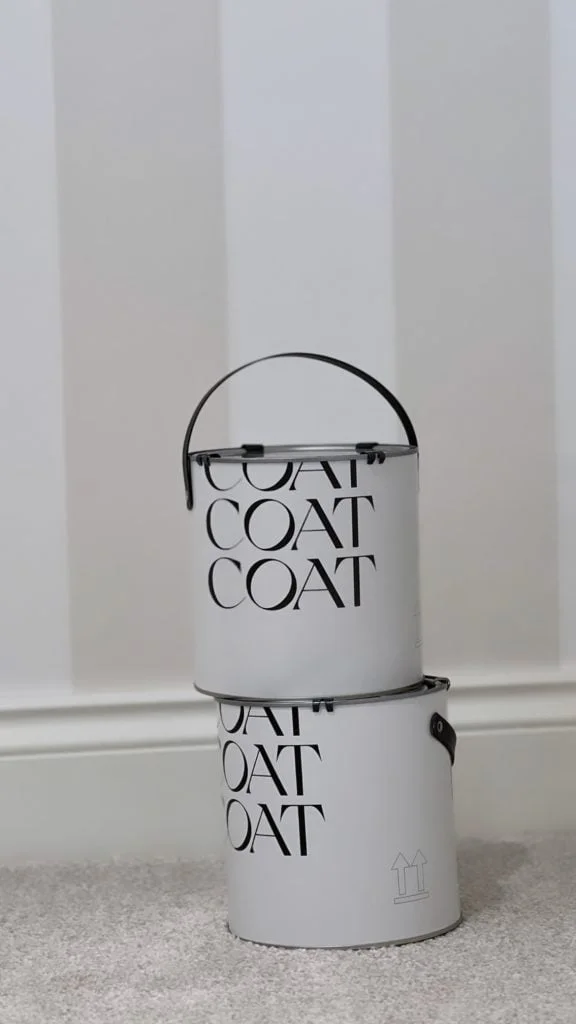 coat paints and paint tins against a wallpapered wall